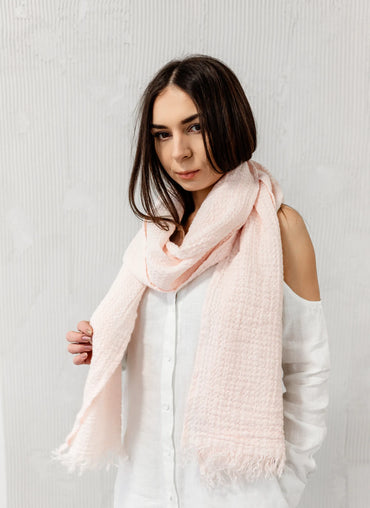 Soft pink Cabana Linen Scarf elegantly draped around a model’s neck, highlighting its delicate texture.