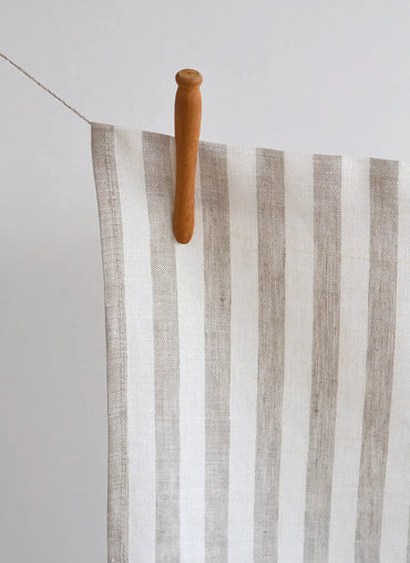 Striped towel hanging on a wooden clothespin against a white background