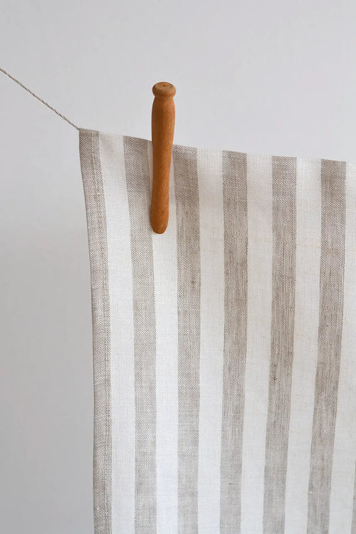Striped towel hanging on a wooden clothespin against a white background