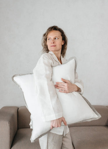 Woman embracing the Adelaide Pillow Cover, a luxurious linen pillowcase with elegant piping, perfect for cozy home decor