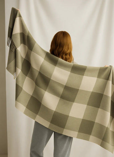 Person holding a green and white checkered blanket against a plain background