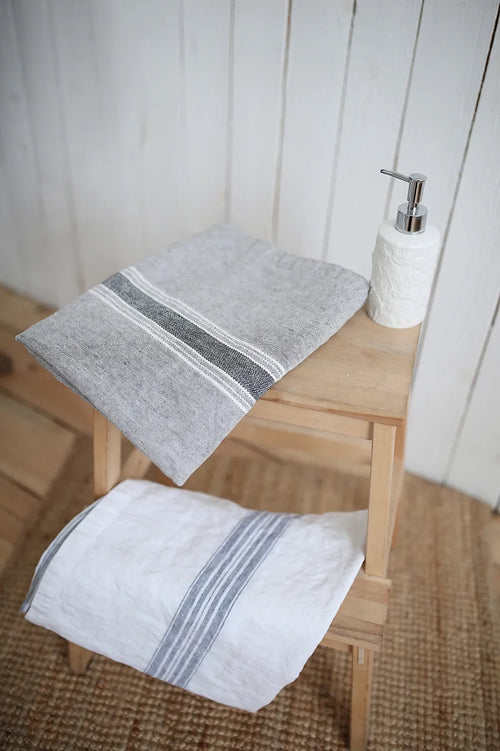 Casa Linen Guest Towels in natural and grey tones, neatly folded on a wooden stool