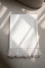 Paris Baby Alpaca Throw in cream color, neatly folded with fringed edges