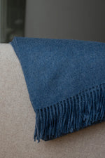 Paris Baby Alpaca Throw in navy blue, draped over an armchair for a cozy look